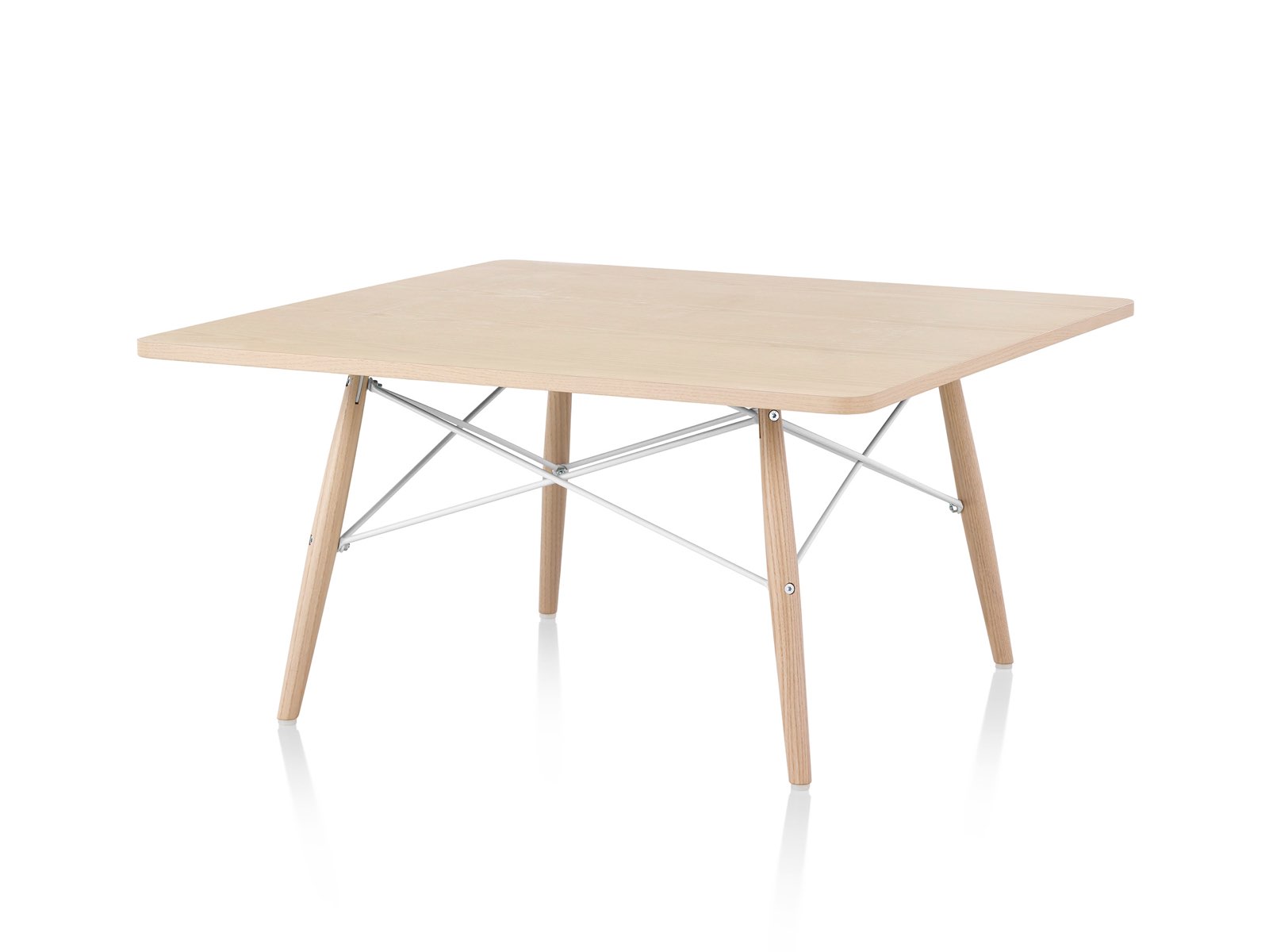An angled view of an Eames Coffee Table with wood legs, metal cross-struts, and a light wood top. 