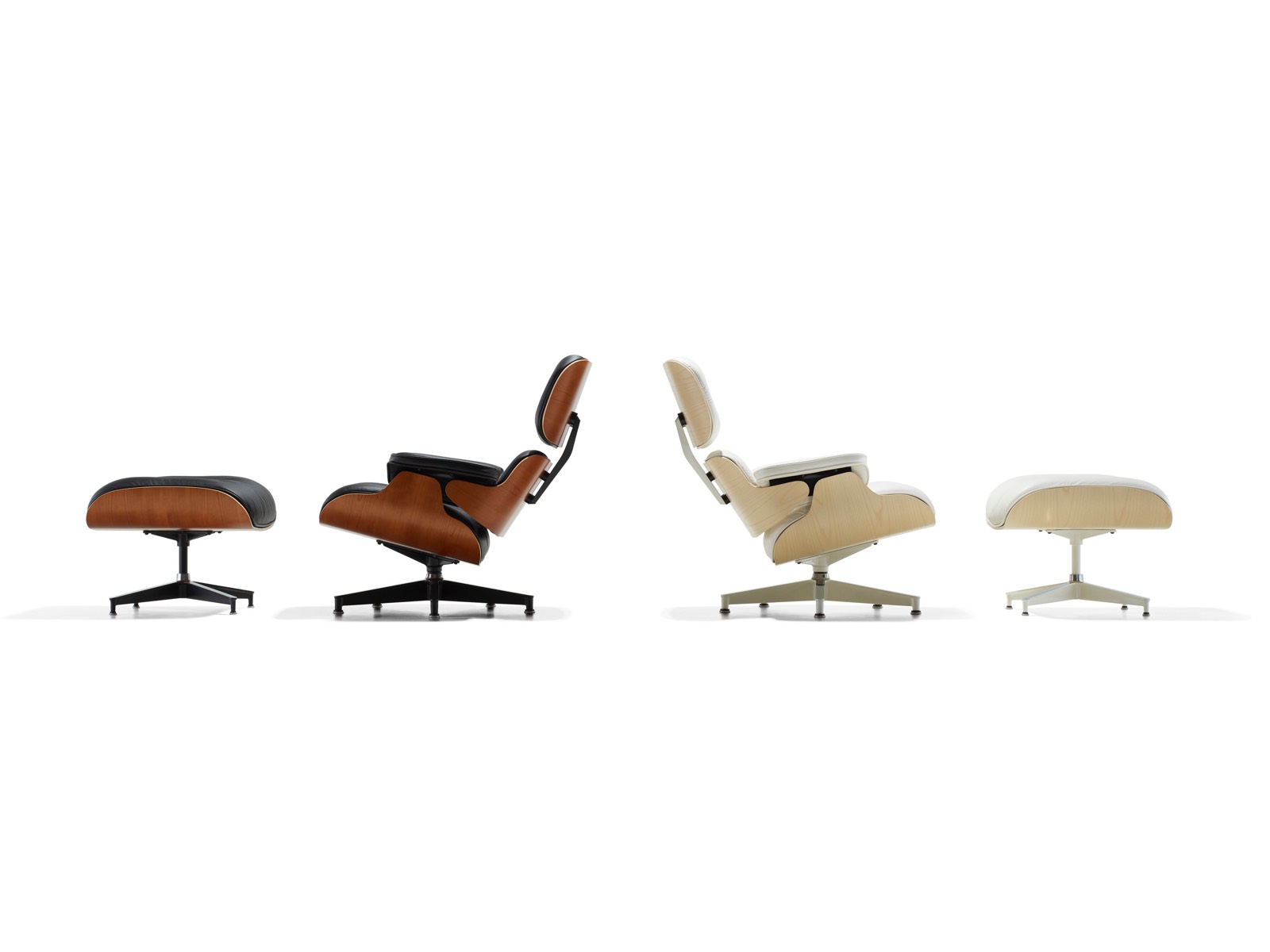 A black leather Eames Lounge Chair and Ottoman and a white leather Eames Lounge Chair and Ottoman, positioned back to back. 